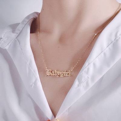 Gold 'Baby girl' necklace on a white shirt