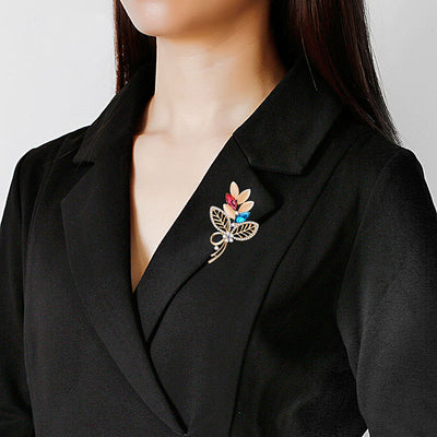 Person wearing a black blazer with a decorative brooch on a plain background