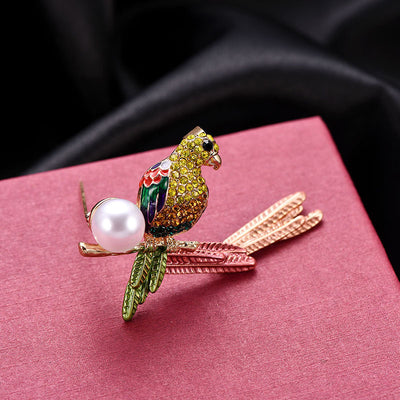Decorative parrot brooch with a pearl on a pink surface