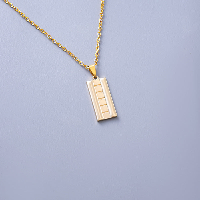 Gold necklace with a rectangular pendant on a light purple background
