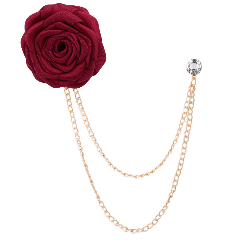 Red rose-shaped brooch with gold chain on a white background