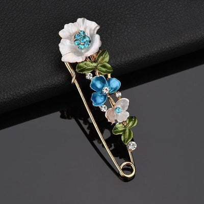 Floral brooch with white, blue, and pink flowers on a dark background