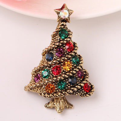 Gold Christmas tree brooch with colorful gemstones on a white background