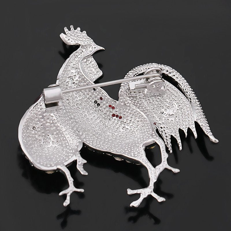 Back side view of the rooster-shaped brooch with gemstones on a black background