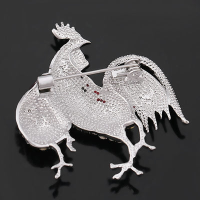 Back side view of the rooster-shaped brooch with gemstones on a black background