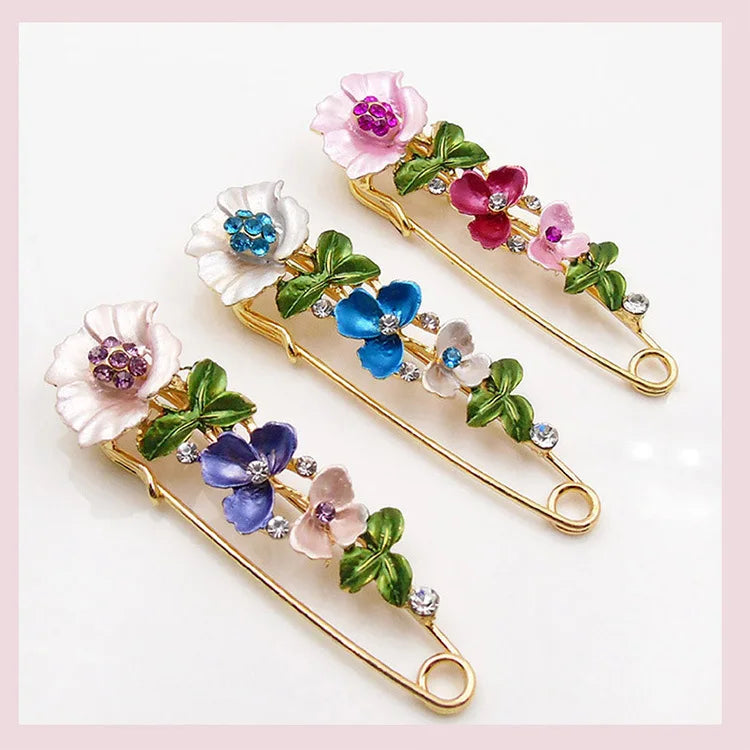 Decorative safety pins with floral designs on a white background