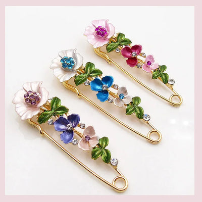 Decorative safety pins with floral designs on a white background