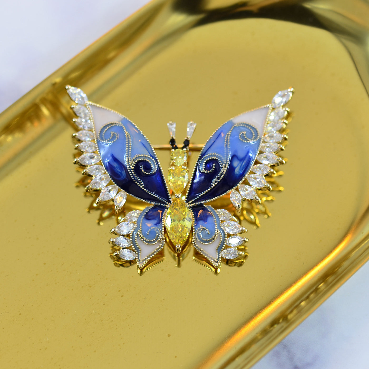 Butterfly-shaped jewelry with blue and white details on a gold background