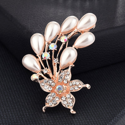 Decorative brooch with pearl-like stones and rose gold accents on a black background