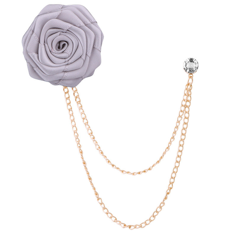 Gray rose-shaped brooch with gold chain on a white background