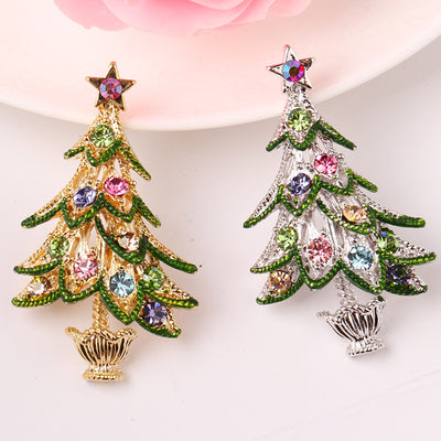 Christmas tree-shaped earrings with colorful gemstones on a light pink background