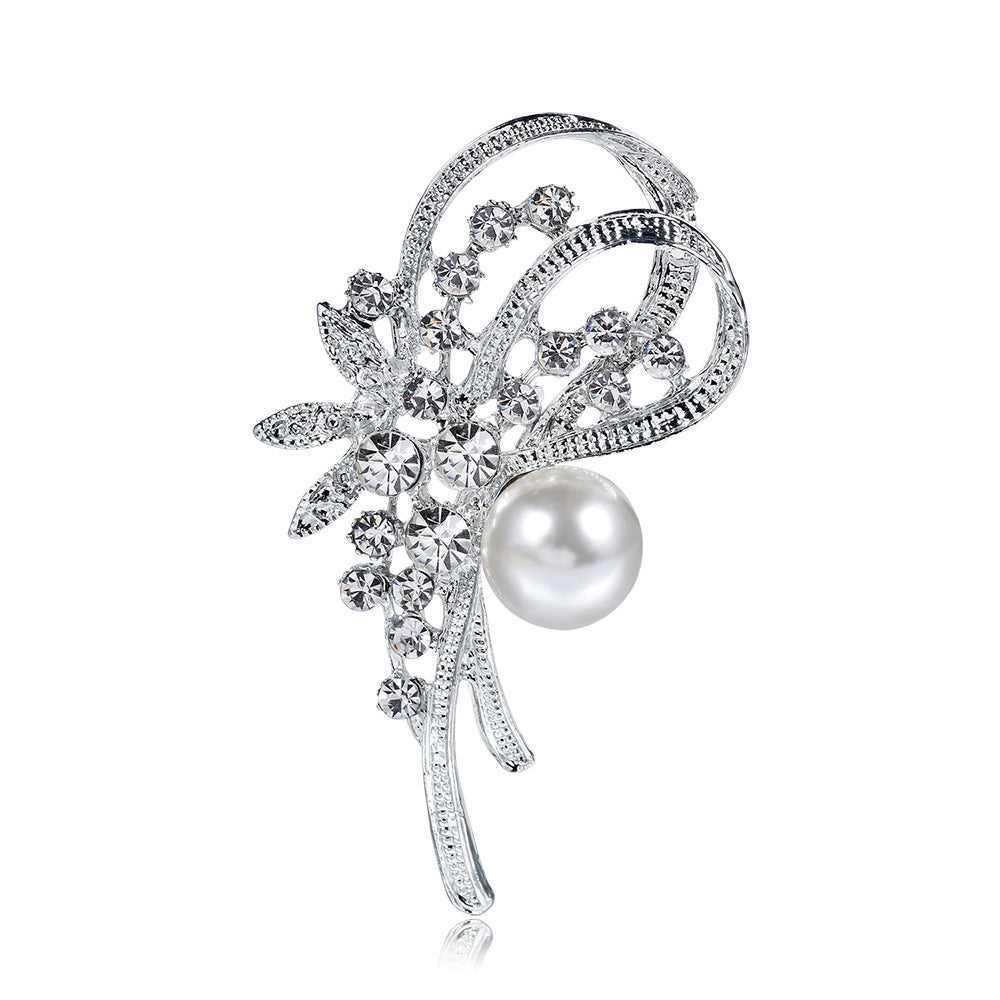 Silver brooch with floral design and pearl on a white background