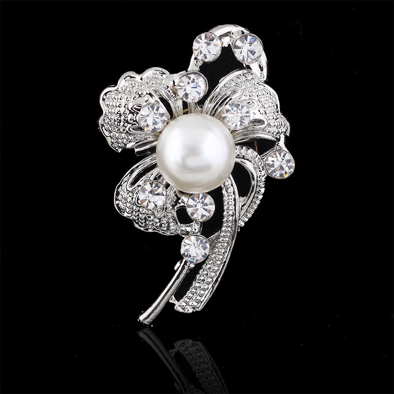 Silver brooch with a pearl and crystals on a black background