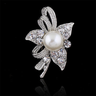 Decorative brooch with pearl and crystals on a black background