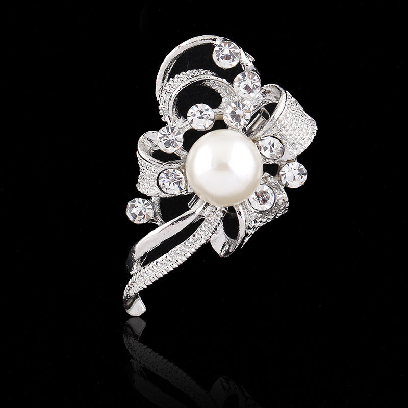 Silver brooch with a pearl and crystals on a black background
