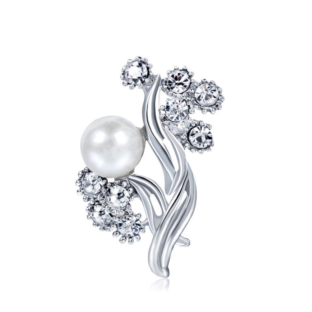 Silver brooch with a pearl and crystal embellishments on a white background