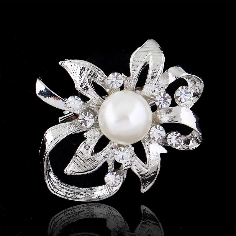 Silver brooch with a pearl and crystals on a black background