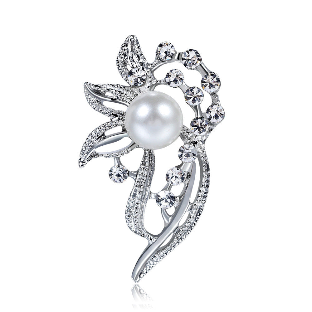 Silver brooch with a pearl and crystal accents on a white background