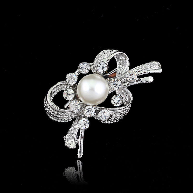 Silver brooch with a pearl and crystals on a black background