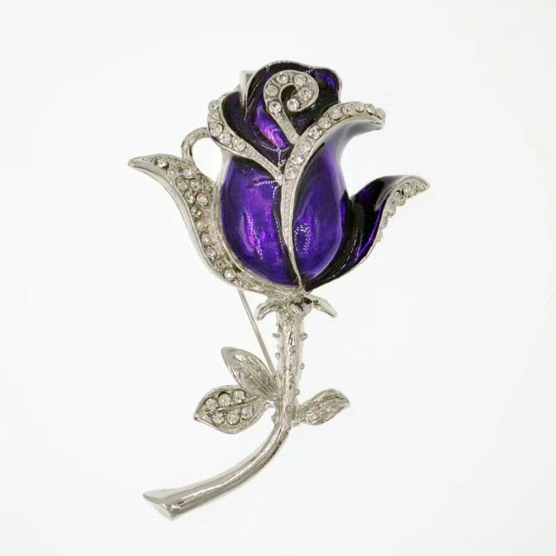 Purple rose-shaped brooch with silver detailing on a white background