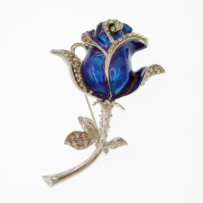 Blue rose brooch with silver detailing on a white background