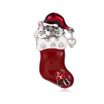 Christmas-themed brooch with red stocking, Santa hat, and decorative elements on a white background