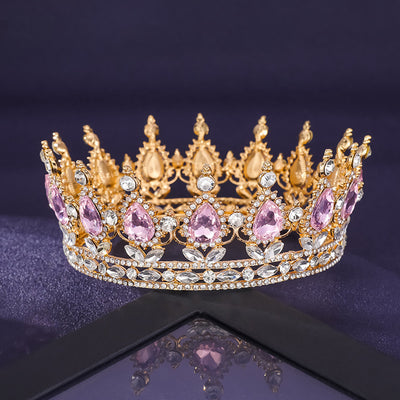 Gold and pink gemstone tiara on a reflective surface with a dark background