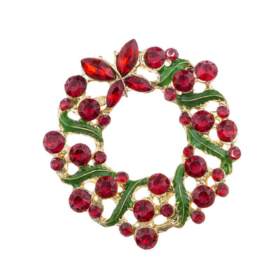 Christmas wreath brooch with red gemstones and gold accents on a white background