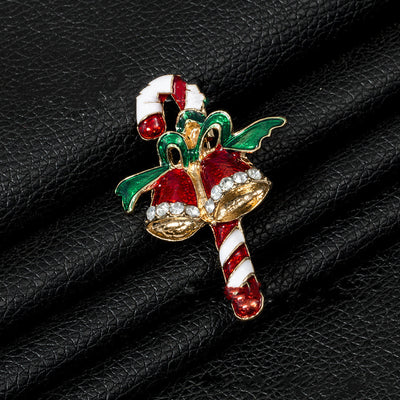 Christmas-themed brooch with candy cane and bell design on a black leather surface