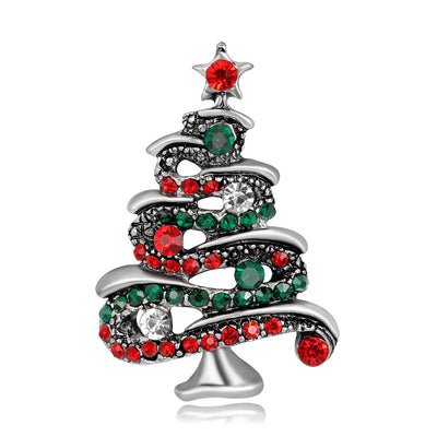 Christmas tree-shaped brooch with red and green gemstones on a white background