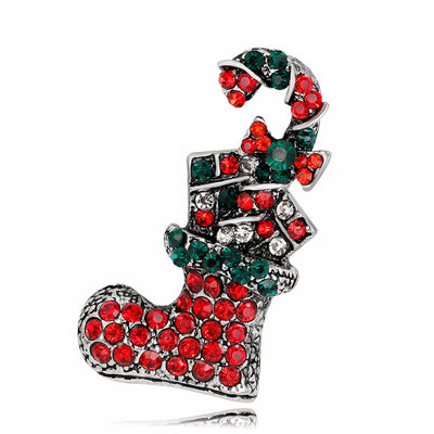 Decorative brooch shaped like a Christmas stocking with red and green gemstones on a white background