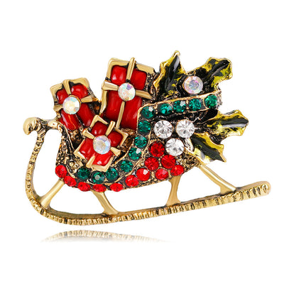 Decorative brooch shaped like a sleigh with red, green, and gold colors on a white background