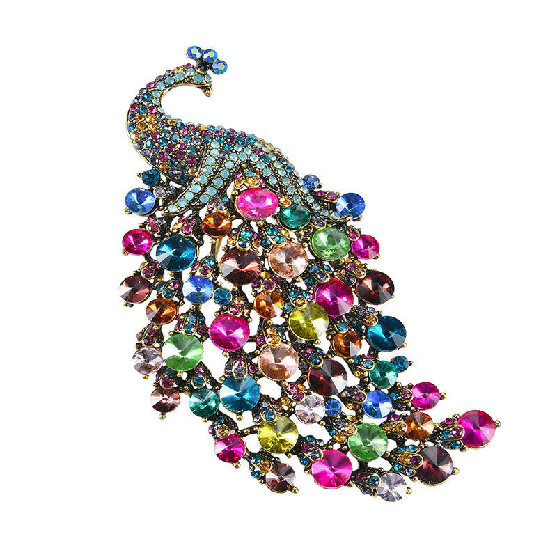 Multicolored jeweled peacock brooch on a white background