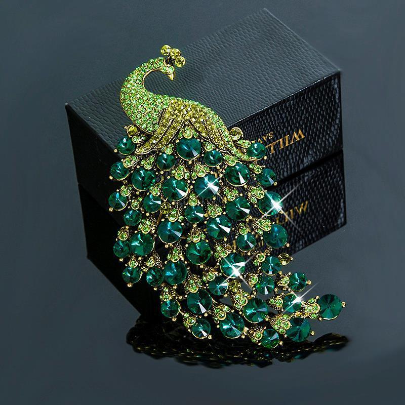 Green peacock-shaped brooch with green gemstones on a dark background