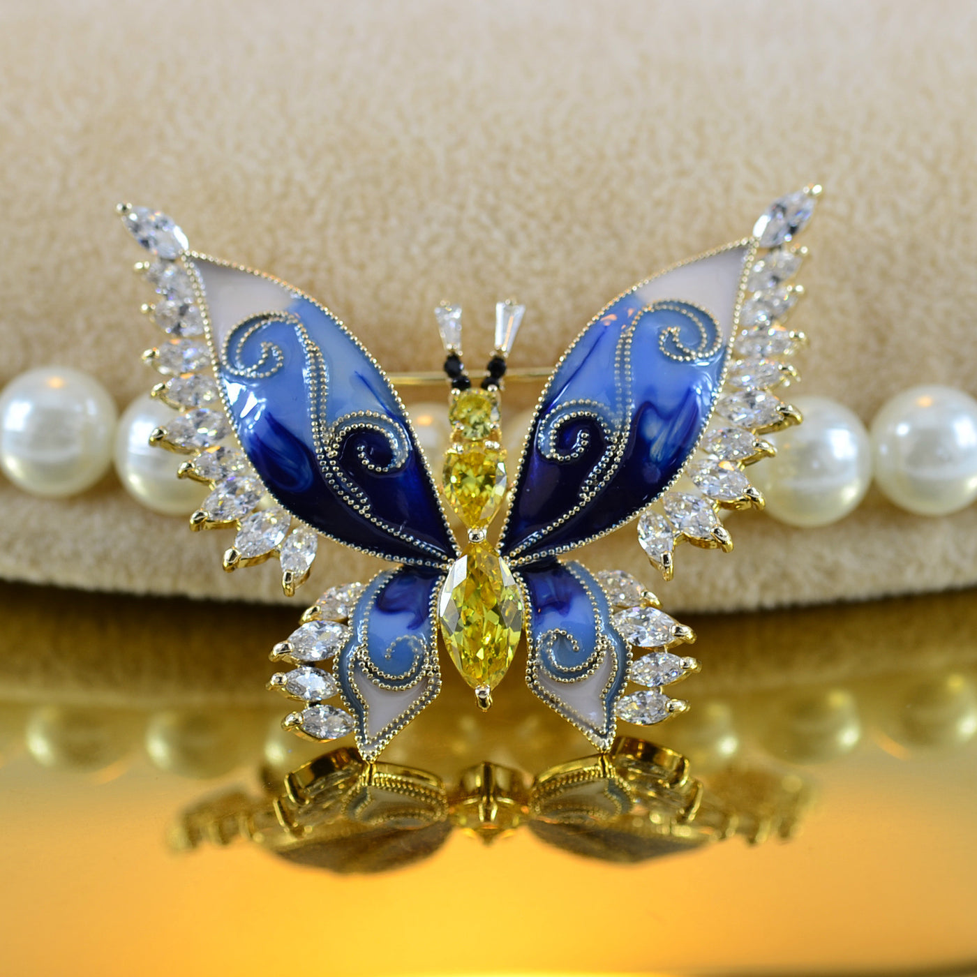 Butterfly-shaped jewelry with blue and gold colors on a beige background
