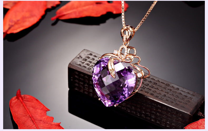 Purple heart-shaped gemstone necklace on a dark surface with red leaves