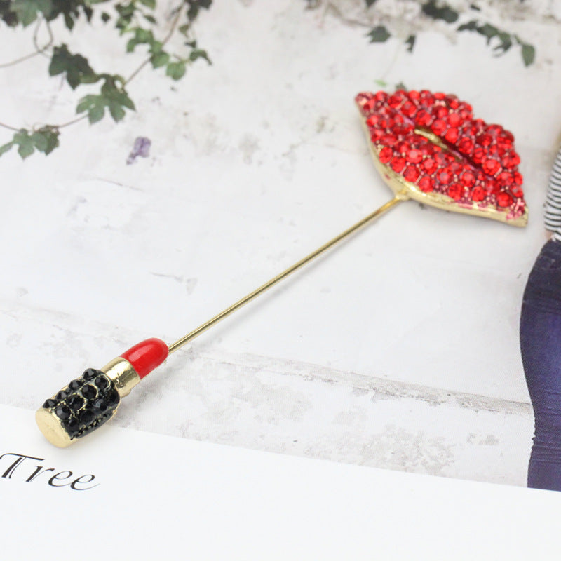 Lipstick-shaped brooch with red and black design on a white background with leaves 