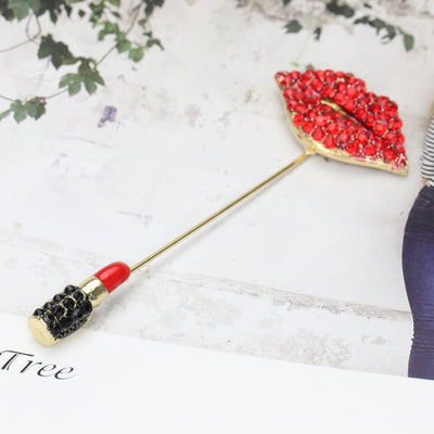 Lipstick-shaped brooch with red and black design on a white background with leaves 