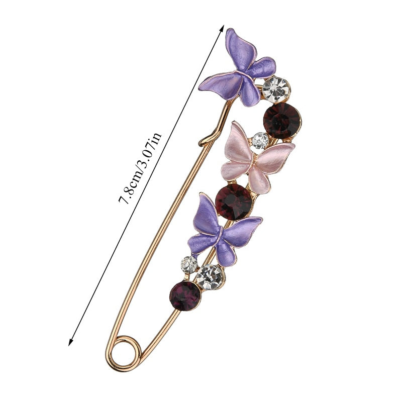 Butterfly-shaped brooch with crystals on a white background