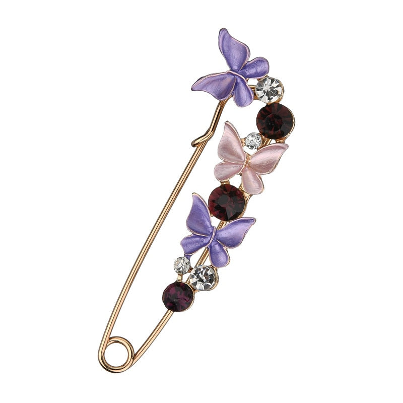 Decorative brooch with butterflies and gemstones on a white background