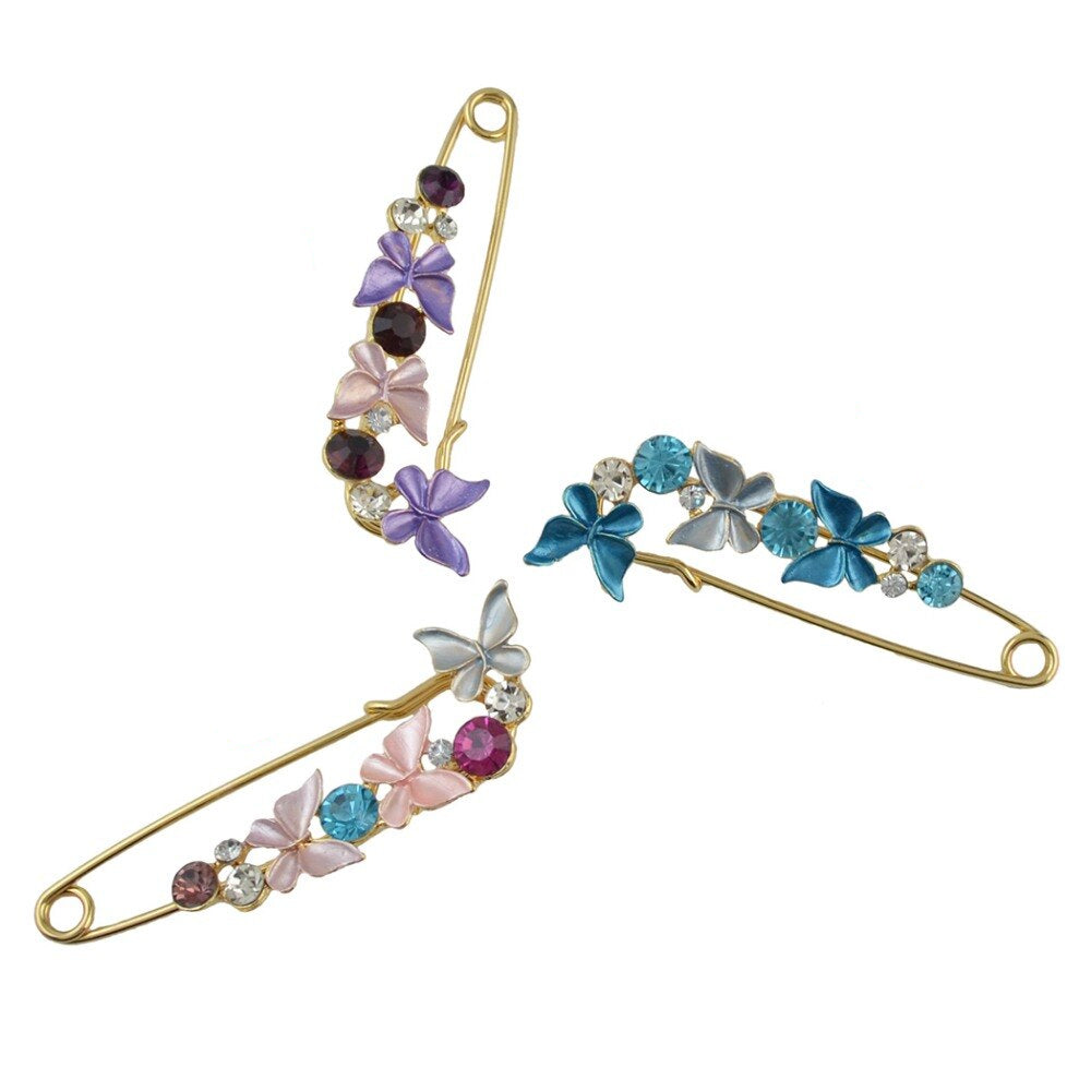 Three decorative safety pins with colorful butterfly designs on a white background.