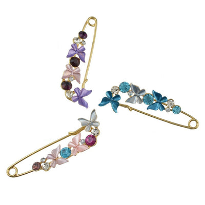 Three decorative safety pins with colorful butterfly designs on a white background.