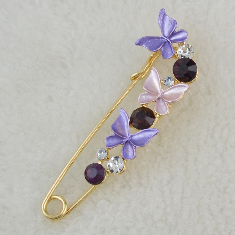 Decorative brooch with purple butterflies and gemstones on a light background