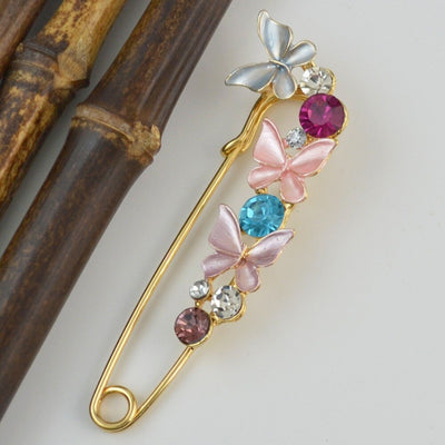 Decorative brooch with butterflies and gemstones on a light background