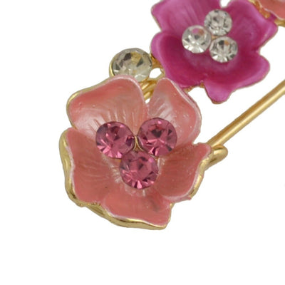 close up of a Floral brooch with pink flowers and gemstones on a white background