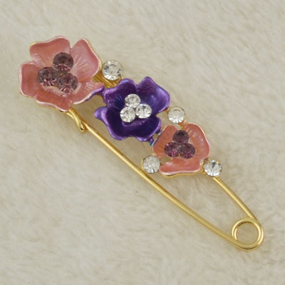 Decorative brooch with floral designs and crystals on a beige background