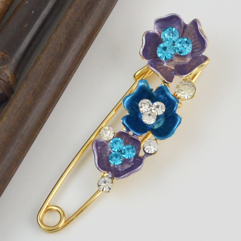 Decorative brooch with purple and blue flowers on a white background