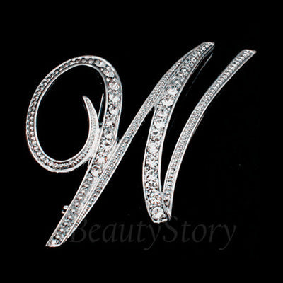 Silver brooch with letter 'W' design on a black background