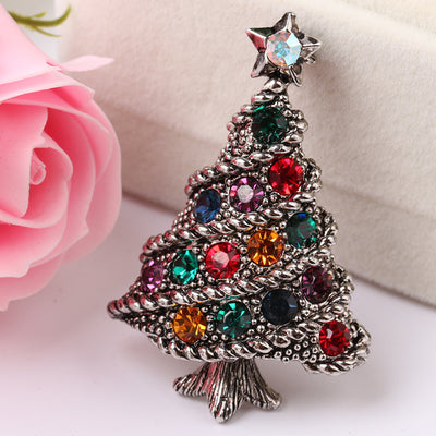Decorative Christmas tree brooch with colorful gemstones on a light background