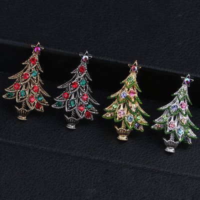 Four Christmas tree-shaped brooches with colorful gemstones on a black background